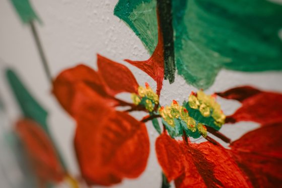 A close up of the details of leaves in a painting of poinsettias.